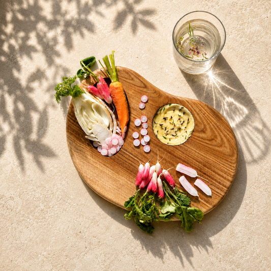 Planche Empreinte en bois massif garnie de légumes croquants et beurre aux herbes pour un apéritif végétal raffiné.